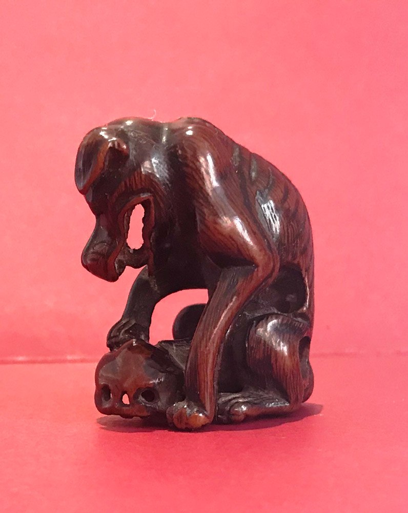 Wood netsuke of a Yama-inu (wild dog) with a skull